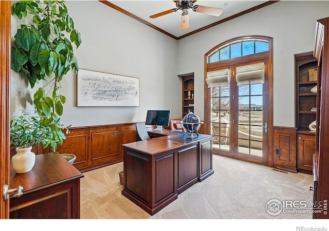 office with a ceiling fan, ornamental molding, light colored carpet, and wainscoting