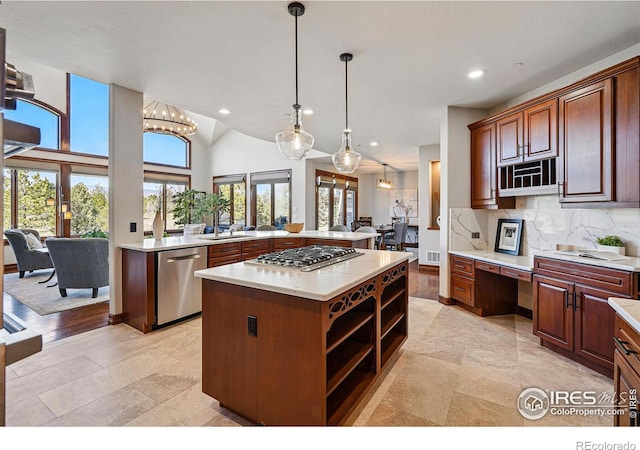 kitchen with backsplash, a kitchen island, light countertops, appliances with stainless steel finishes, and a sink