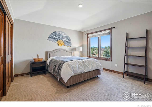 bedroom featuring light carpet, a closet, and baseboards
