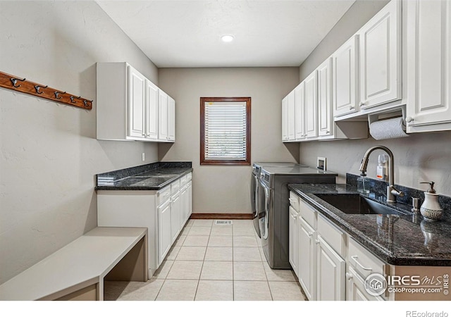 laundry area with independent washer and dryer, a sink, cabinet space, light tile patterned floors, and baseboards