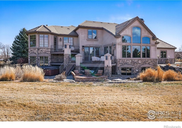 rear view of property with stucco siding, stone siding, a patio, and stairs