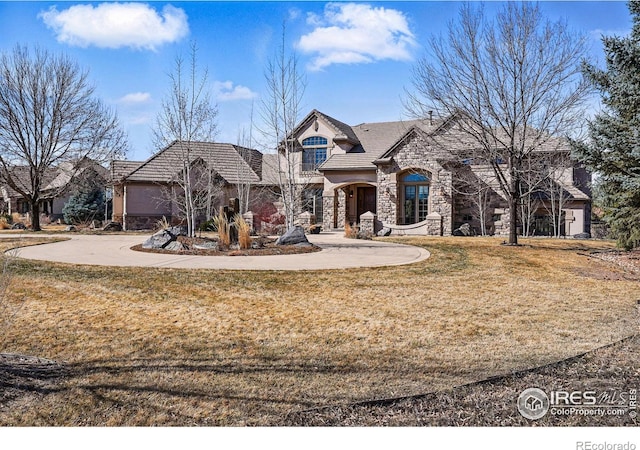 view of front of home featuring stucco siding, stone siding, and a front yard