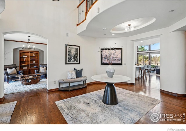 dining area featuring baseboards, arched walkways, wood finished floors, and crown molding