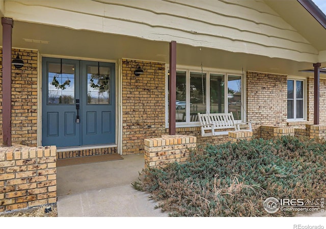 doorway to property featuring brick siding and covered porch
