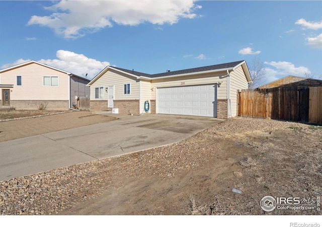 single story home featuring brick siding, concrete driveway, a garage, and fence