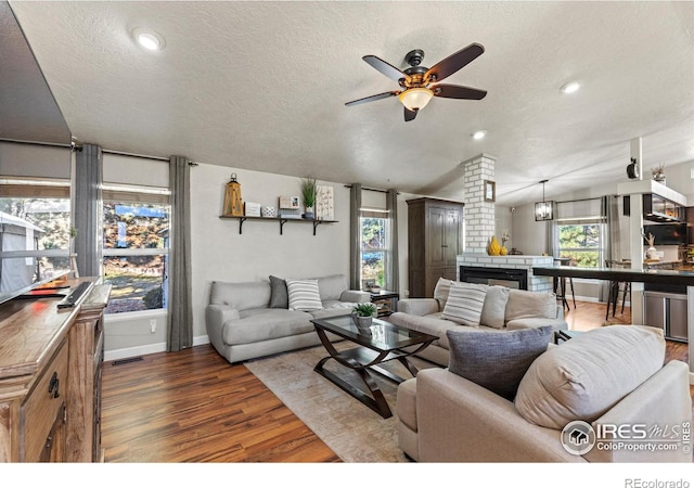 5621 W 27th St, Greeley, CO 80634 - living area featuring a textured ceiling, recessed lighting, a brick fireplace, ceiling fan, and dark wood-style flooring