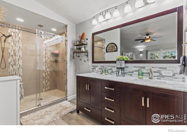 5621 W 27th St, Greeley, CO 80634 - bathroom featuring tasteful backsplash, a stall shower, ceiling fan, and a sink