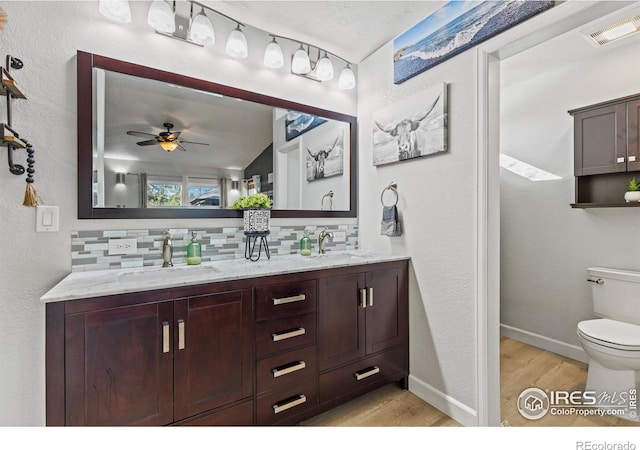5621 W 27th St, Greeley, CO 80634 - full bathroom featuring visible vents, backsplash, toilet, wood finished floors, and a sink