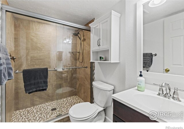 5621 W 27th St, Greeley, CO 80634 - full bathroom featuring vanity, a shower stall, toilet, and a textured ceiling