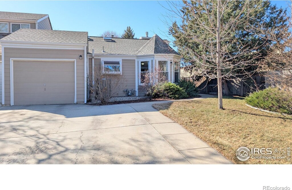 view of front of home with a front lawn, an attached garage, driveway, and roof with shingles