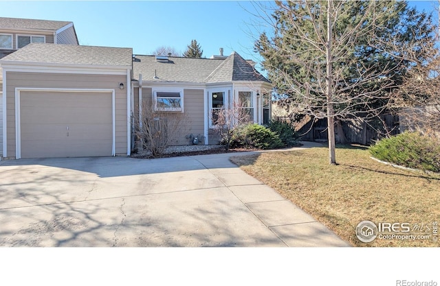 view of front of home with a front lawn, an attached garage, driveway, and roof with shingles