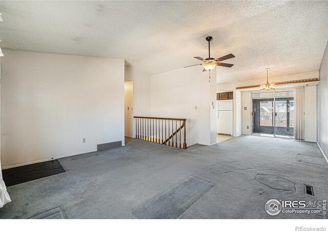 carpeted empty room with lofted ceiling, ceiling fan with notable chandelier, visible vents, and a textured ceiling