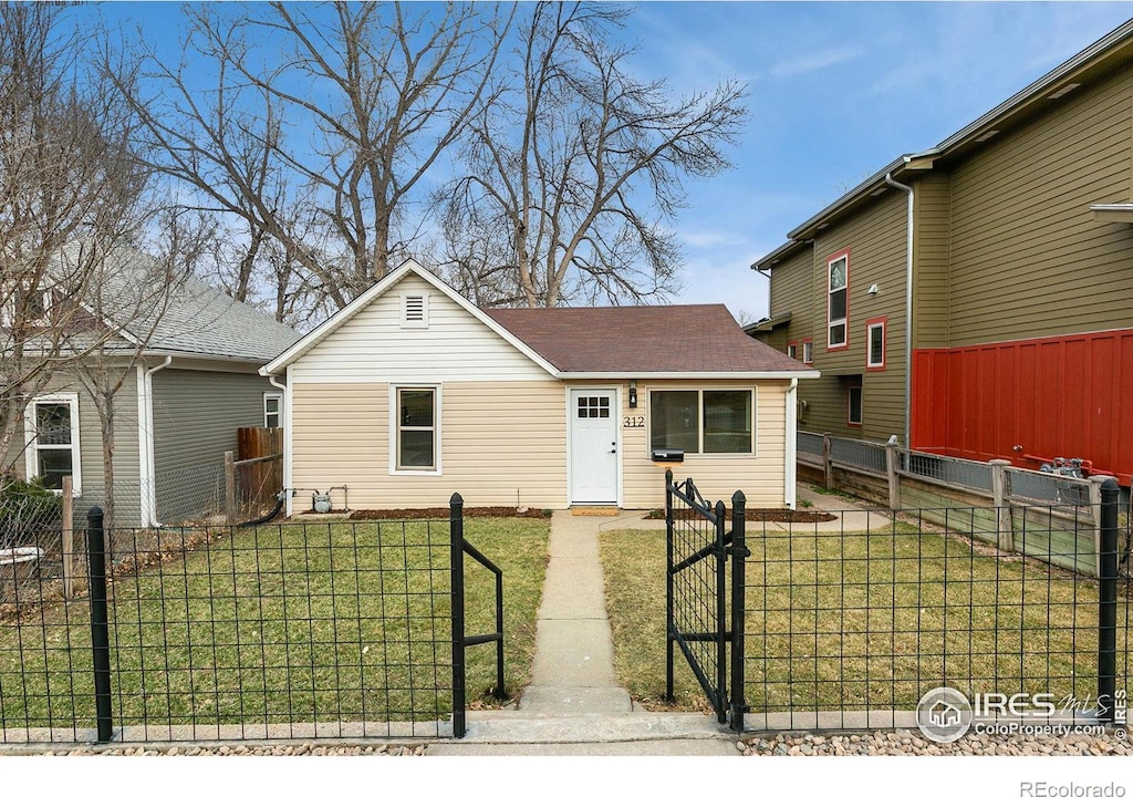 view of front of property featuring a fenced front yard, a front lawn, and a shingled roof