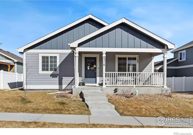 bungalow-style home featuring a porch, fence, and board and batten siding
