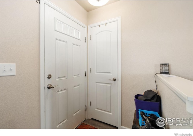 laundry area featuring a textured wall and wood finished floors
