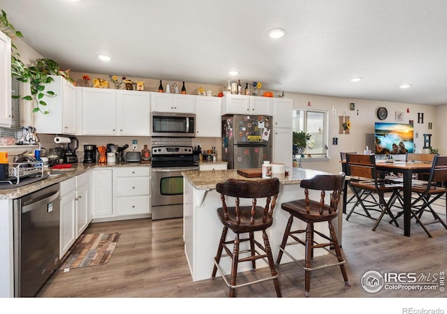 kitchen featuring light wood finished floors, white cabinets, appliances with stainless steel finishes, and a kitchen island