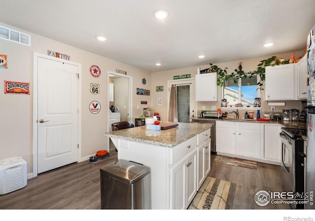 kitchen with wood finished floors, white cabinets, stainless steel appliances, and a sink