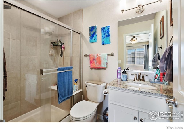 bathroom featuring a shower stall, vanity, toilet, and a ceiling fan