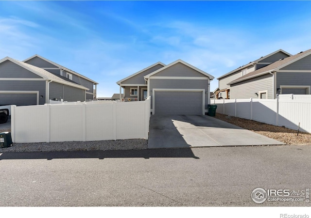 view of front of property with concrete driveway, fence, and a garage