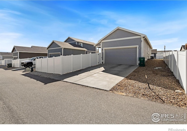 view of side of property with an attached garage, concrete driveway, and fence