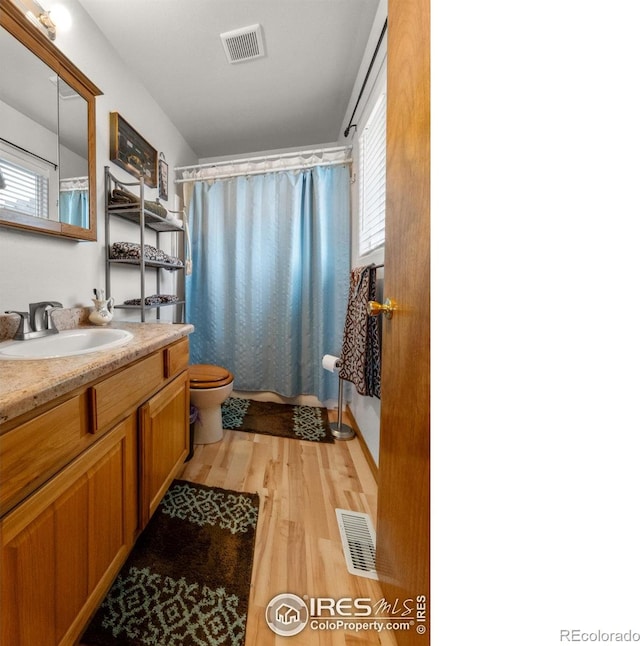 562 E St, Hillrose, CO 80733 - full bathroom with toilet, wood finished floors, vanity, and visible vents