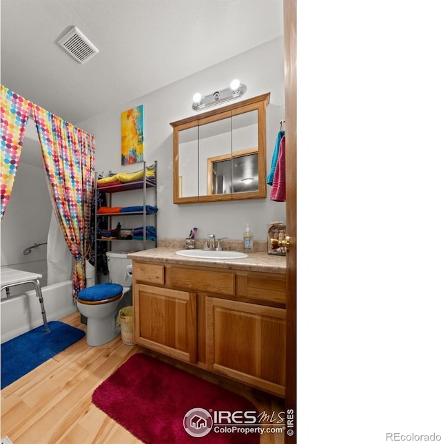 562 E St, Hillrose, CO 80733 - full bath with visible vents, shower / bath combination with curtain, toilet, vanity, and wood finished floors