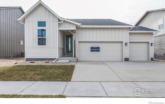 view of front facade with driveway, roof with shingles, board and batten siding, and an attached garage