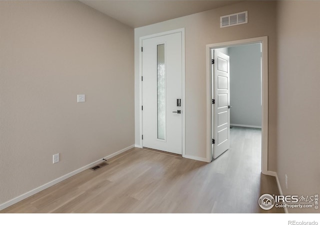 foyer entrance featuring visible vents, baseboards, and light wood-style flooring