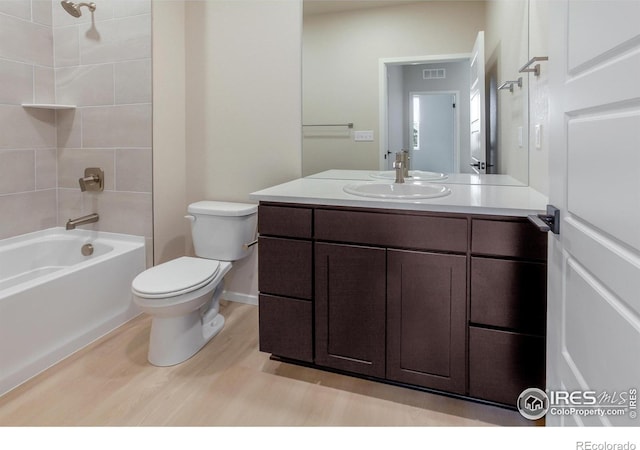 bathroom featuring visible vents, toilet, bathtub / shower combination, wood finished floors, and vanity