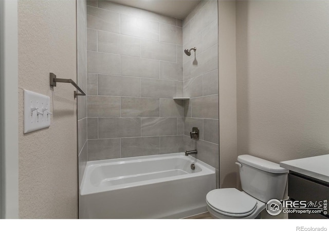 bathroom featuring shower / washtub combination, toilet, vanity, and a textured wall