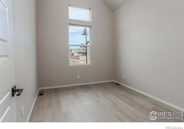 unfurnished room featuring visible vents, baseboards, lofted ceiling, and wood finished floors