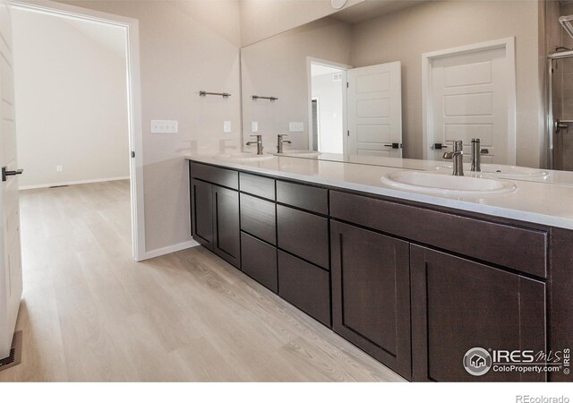 full bath featuring double vanity, wood finished floors, and a sink