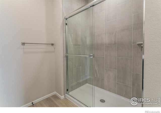 full bathroom with baseboards, wood finished floors, and a stall shower