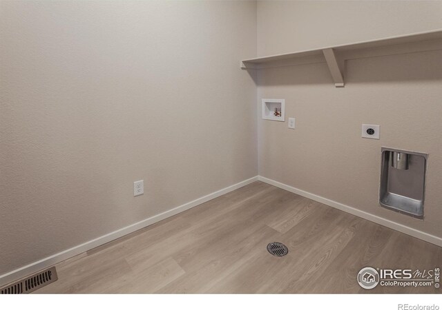 washroom with hookup for a washing machine, wood finished floors, visible vents, baseboards, and laundry area
