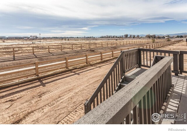 deck with a rural view and fence