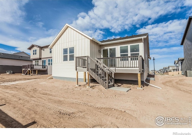back of property with board and batten siding and a deck