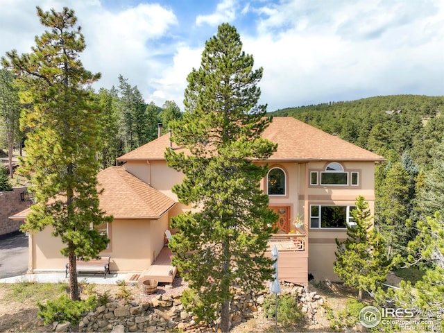 12023 Coal Creek Heights Dr, Golden, CO 80403 - view of front of home with a forest view, stucco siding, and roof with shingles