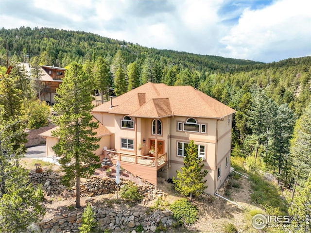 12023 Coal Creek Heights Dr, Golden, CO 80403 - rear view of property with a forest view, stucco siding, a shingled roof, and a deck
