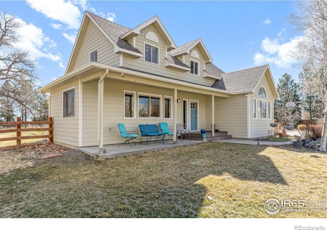 view of front of home featuring a patio, a shingled roof, a front yard, and fence