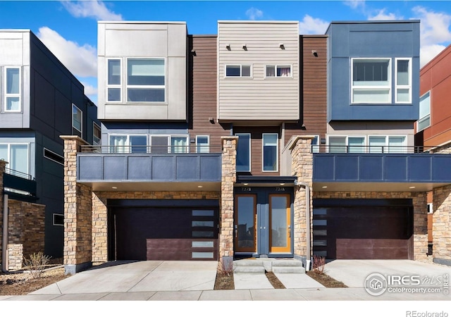 modern home featuring stucco siding, stone siding, concrete driveway, an attached garage, and a balcony