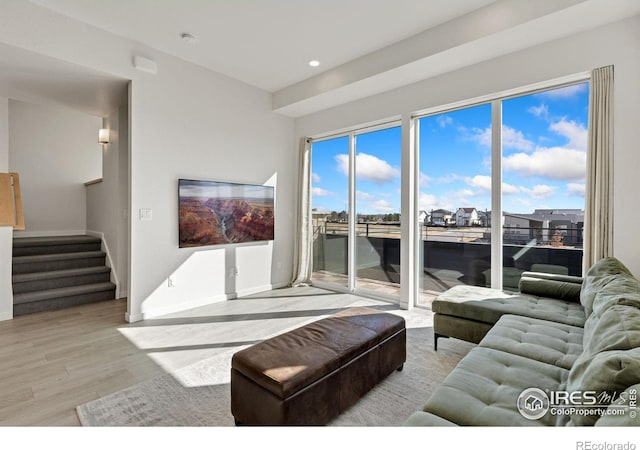 living room featuring recessed lighting, baseboards, wood finished floors, and stairs