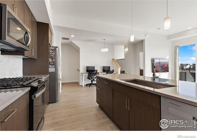 kitchen with tasteful backsplash, visible vents, light wood-style flooring, appliances with stainless steel finishes, and a sink