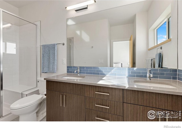 bathroom with decorative backsplash, toilet, a shower with door, and a sink