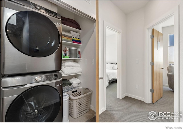 washroom featuring laundry area, stacked washer / dryer, carpet, and baseboards