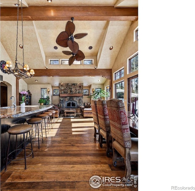 dining room with dark wood-style floors, beam ceiling, ceiling fan with notable chandelier, and high vaulted ceiling