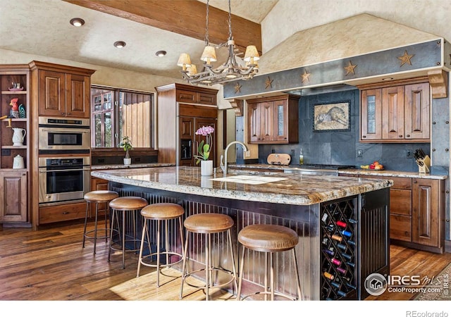kitchen featuring a sink, dark wood-type flooring, a breakfast bar, and a kitchen island with sink