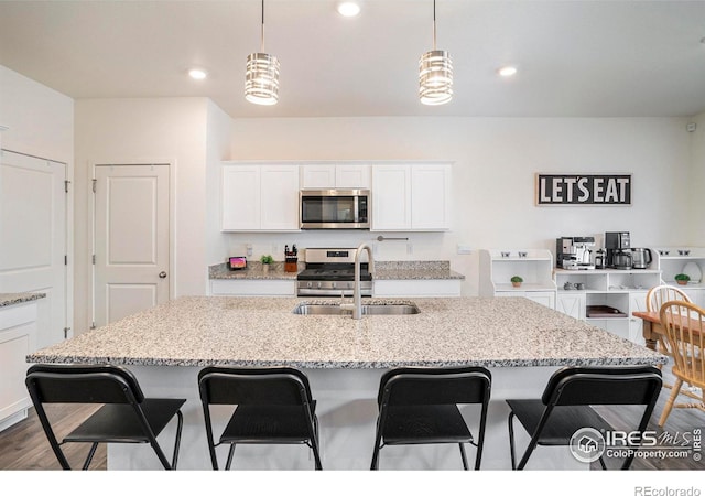 254 Ptarmigan Ln, Johnstown, CO 80534 - kitchen with appliances with stainless steel finishes, a kitchen breakfast bar, white cabinetry, hanging light fixtures, and recessed lighting