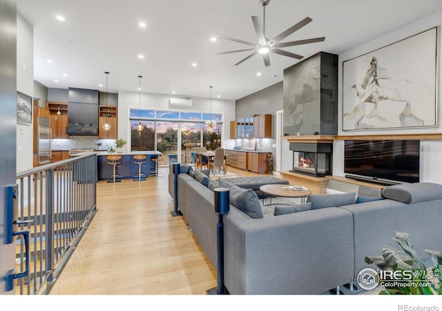 living area with light wood finished floors, recessed lighting, an AC wall unit, and ceiling fan