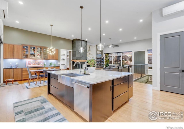 kitchen featuring an AC wall unit, a sink, dishwasher, a spacious island, and light wood-style flooring
