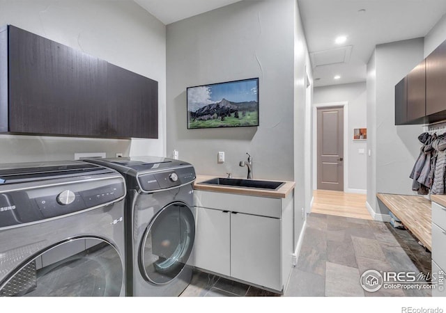 washroom with cabinet space, washer and clothes dryer, stone finish floors, attic access, and baseboards